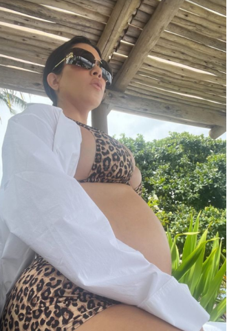 Kourtney Kardashian flaunts her baby bump in a bikini and shares her costly pregnancy cravings.