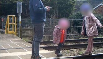 Dad seen on security footage allowing two kids to play on active train tracks.