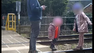 Dad seen on security footage allowing two kids to play on active train tracks.