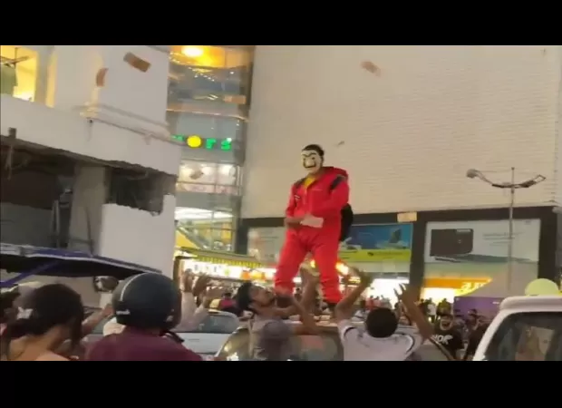 Man in Jaipur arrested after driving around, throwing ₹10 & ₹20 notes from atop his car while wearing 'Money Heist' costume.