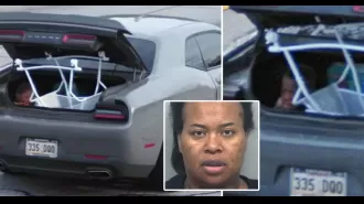 Mother caught driving with son holding down baby bassinet in open car trunk.