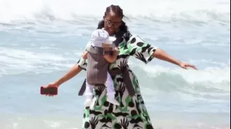 Dance competition celebrity enamored with 7-month-old daughter, twirls and sways with her on the shore.