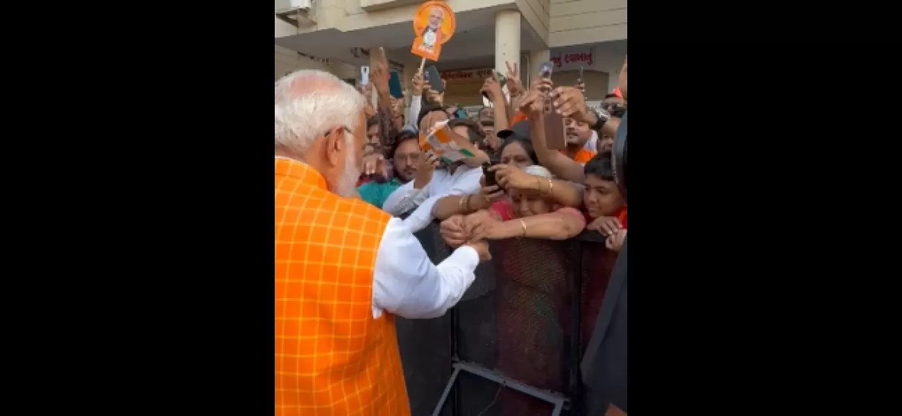 Large crowd gathers as woman ties rakhi to PM Modi at polling booth in Ahmedabad.