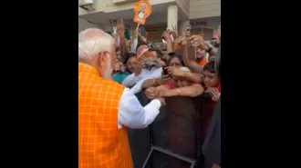 Large crowd gathers as woman ties rakhi to PM Modi at polling booth in Ahmedabad.
