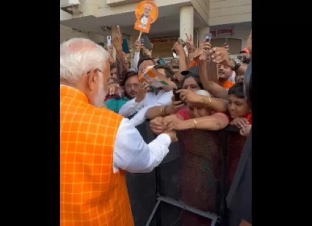 Large crowd gathers as woman ties rakhi to PM Modi at polling booth in Ahmedabad.