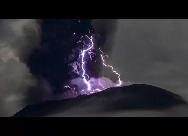 Purple lightning flashes around erupting volcano in stunning images.