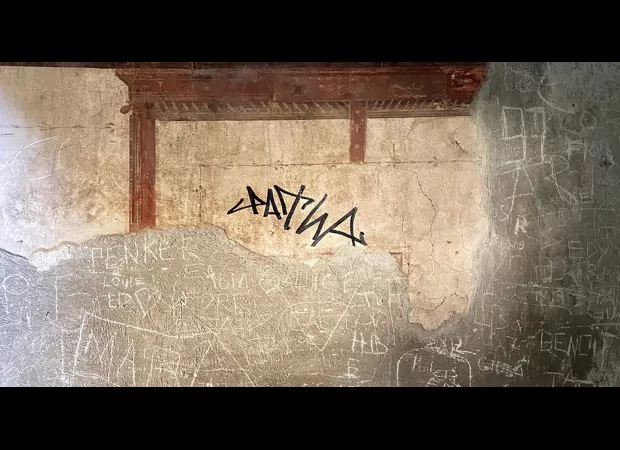 Tourist vandalizes ancient Roman building by writing on it with marker.