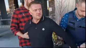 Tommy Robinson arrested for suspected immigration violation, taken away in handcuffs.