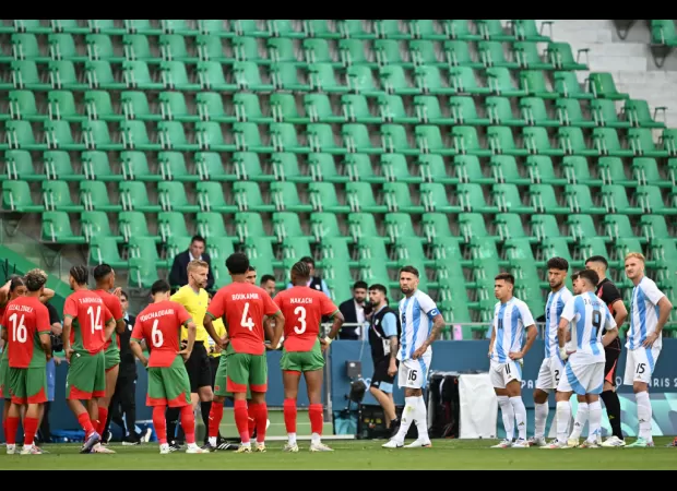 Fans removed from stadium during chaotic Olympics football game due to field intrusion.