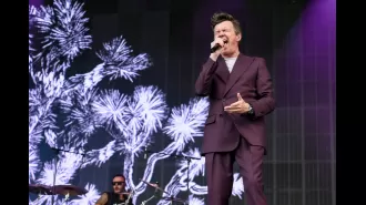An 80s legend sings a disliked song while riding on a trailer at unexpected appearance at Latitude Festival.