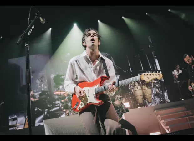 The band 1975 faces lawsuit for $2.4 million after lead singer's onstage kiss sparks controversy.