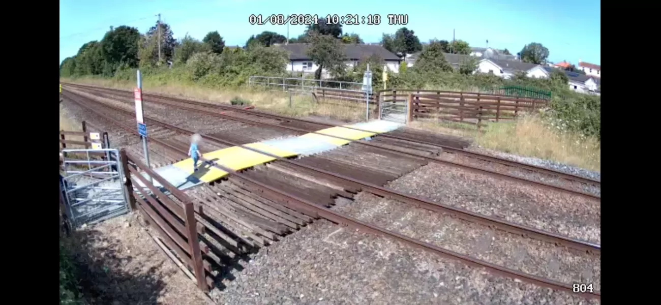 Small child walks out onto crossing by themselves, narrowly missing a train.