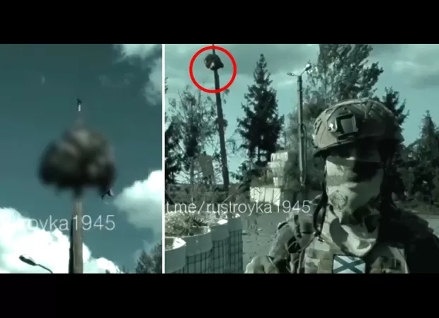 A Russian soldier holds up the decapitated head of a Ukrainian soldier on top of a stake.