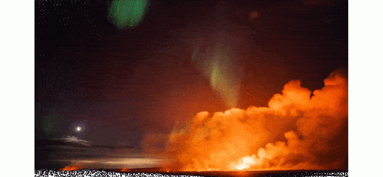 A glowing sky show as aurora borealis illuminates erupting volcano.