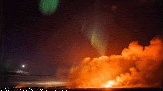 A glowing sky show as aurora borealis illuminates erupting volcano.