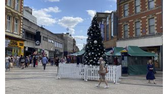 Town center displays Christmas tree unusually early, over 100 days before Christmas.