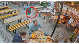 A man eating pizza gets hit by a fish falling from the sky.