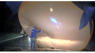 Cop struggles with a huge Halloween pumpkin and gets covered by it.