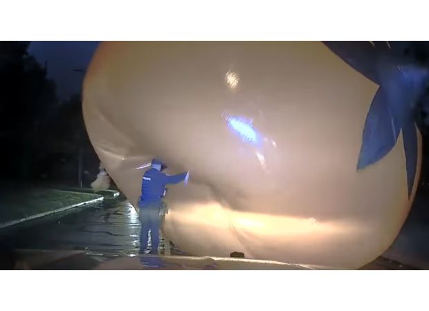 Cop struggles with a huge Halloween pumpkin and gets covered by it.