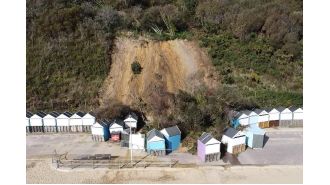 A landslide narrowly misses tourists as it crashes onto a well-known beach.