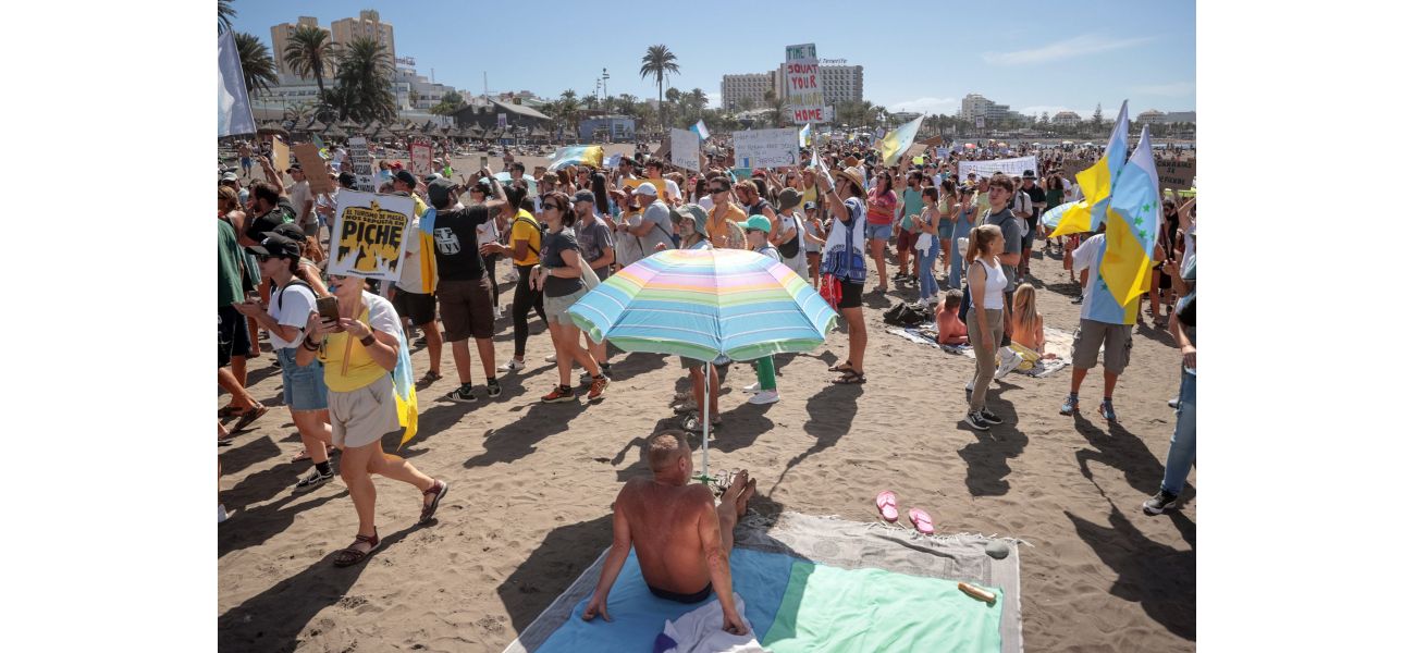 As tourists watch, demonstrators against tourism march through the Canary Islands during the holidays.