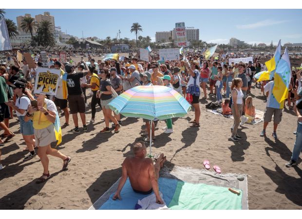 As tourists watch, demonstrators against tourism march through the Canary Islands during the holidays.