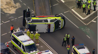 Four people were hurt when an ambulance overturned in Brisbane.