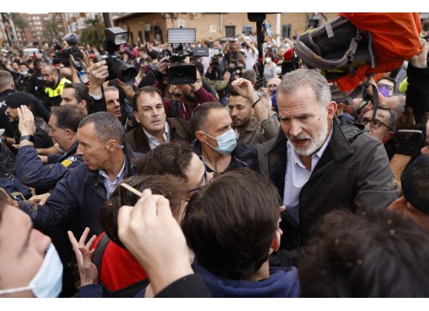Furious flood victims yell and fling dirt at ruler.