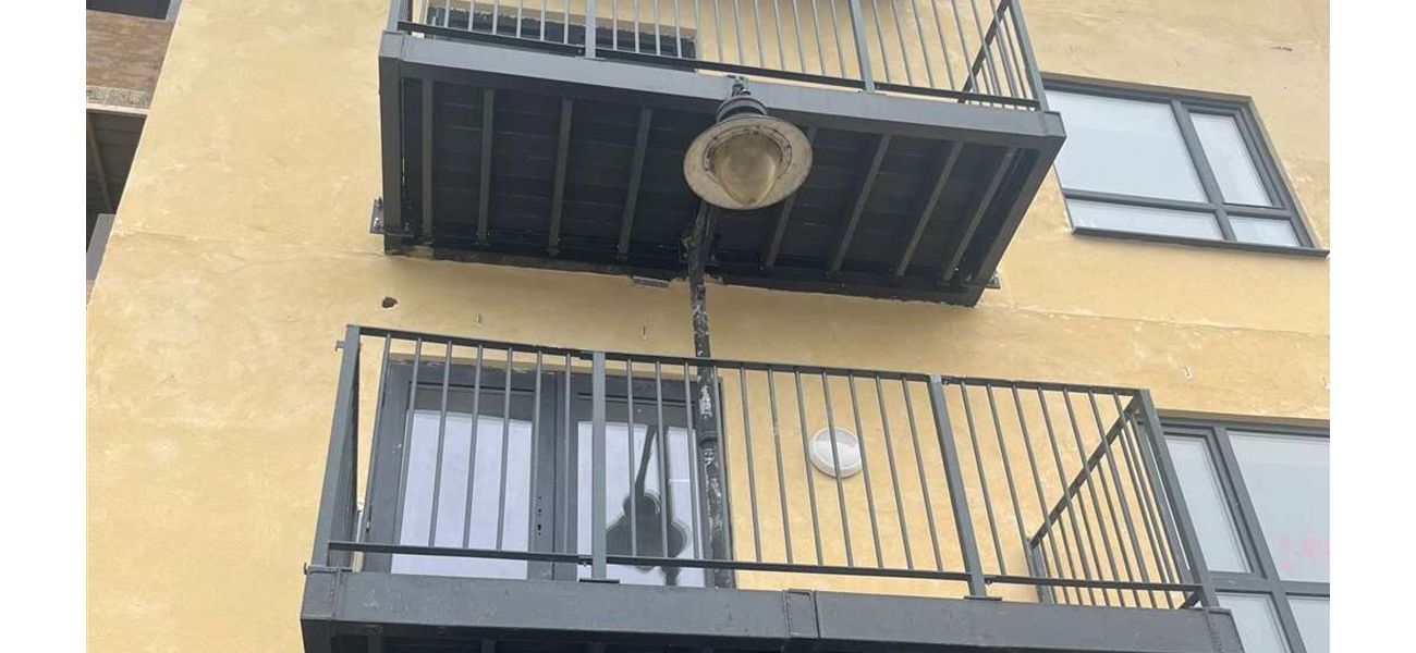 Residents confused by strange balcony construction featuring lamppost passing through it.