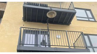 Residents confused by strange balcony construction featuring lamppost passing through it.