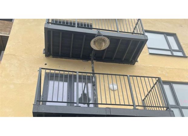 Residents confused by strange balcony construction featuring lamppost passing through it.
