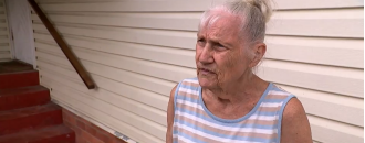 Possible paraphrase: A car, believed to be stolen, crashes into a house in Queensland, causing great distress to a woman.