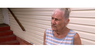 Possible paraphrase: A car, believed to be stolen, crashes into a house in Queensland, causing great distress to a woman.