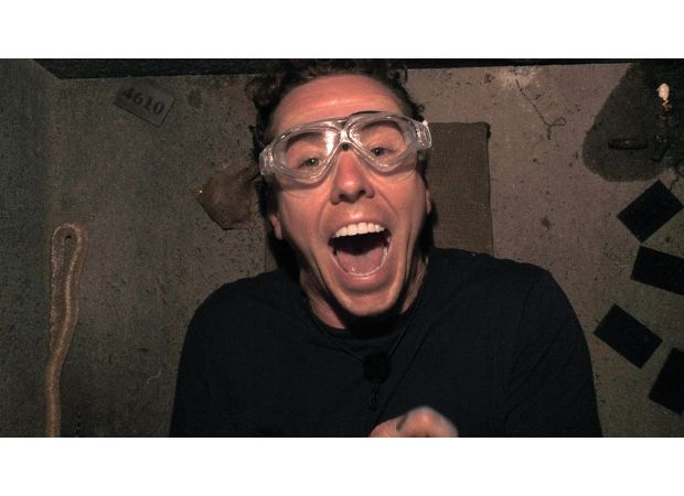 A celebrity on a reality show reveals a large snake by pulling down their shorts.