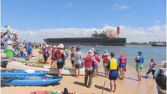 Protesters stop coal ships using surfboards and kayaks at port.