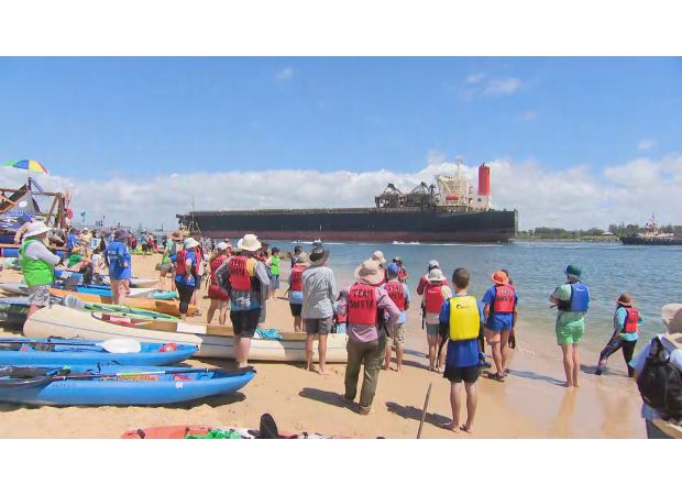 Protesters stop coal ships using surfboards and kayaks at port.