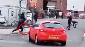 Students wielding machetes and large knives chase each other outside of a school.