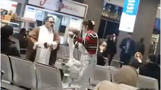 Woman bravely removes mullah's turban for hijab during airport confrontation.