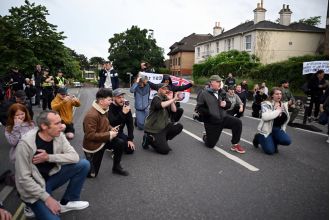 People kneel during vigil for Nowak, following recent riots in Southampton.